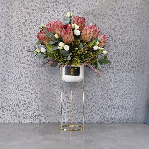 Vista Pink - Height: 70 cm
Width: 50 cm
 A stand contains protea flowers, lisianthus and boronia flowers.