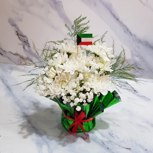 Kuwait National Day 1906 - The white craze flowers are complemented by delicate gypsophilia and a vibrant green tree, creating a visually captivating display. As an added touch, the bouquet is adorned with the Kuwait national flag, adding a touch of national pride to this beautiful arrangement. height 25 cm width 20 cm