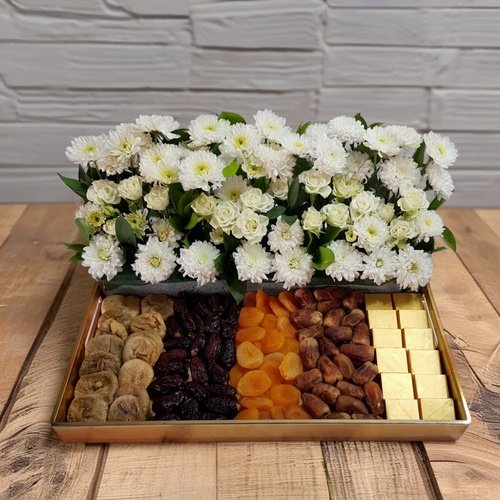 Dry Fruits Flowers Gift Large Tray 1017 - This beautiful tray features a delightful combination of white flowers and dried fruits. The flowers include white craze, baby rose white, and green rescus, while the dried fruits consist of 12 figs, 24 Safawi dates, 24 apricots, and Siqei dates. To add a touch of indulgence, the tray also includes 12 wafer chocolates. 
 With a height of 22 cm and a width of 50 cm 
 this tray is both visually appealing and deliciously satisfying.